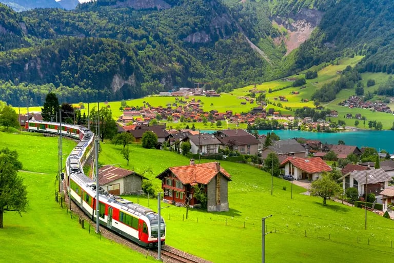 A scenic Swiss train traveling through lush green meadows and a mountain village near a blue lake.