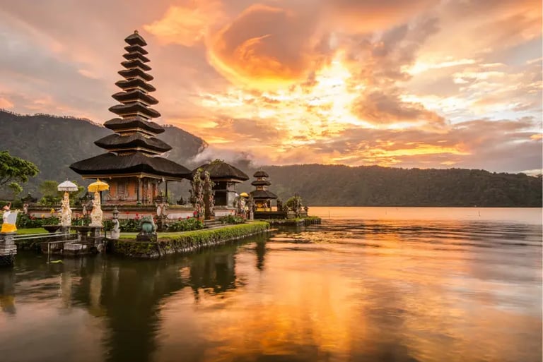 Sunset view of Ulun Danu Beratan Temple on a lake in Bali, Indonesia with mountains.