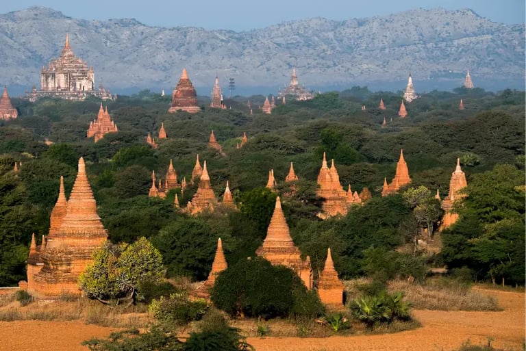 Ancient brick pagodas and Buddhist temples scattered across the lush plains of Bagan, Myanmar.