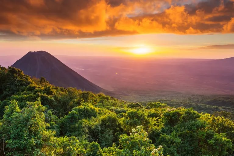 Golden sunset over Izalco Volcano and lush green forest landscape in El Salvador.