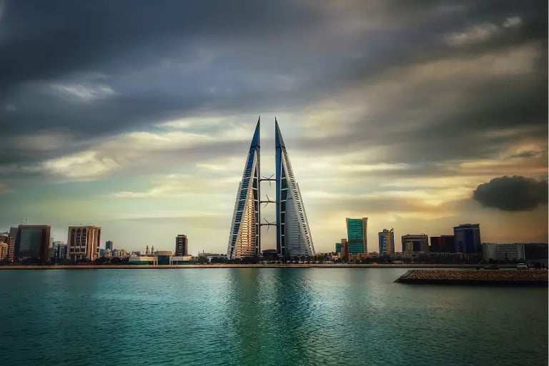 The Bahrain World Trade Center twin towers overlook the Manama skyline and Persian Gulf at sunset.