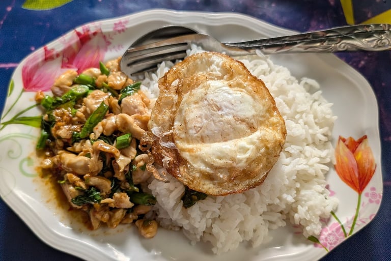 Authentic Thai basil chicken stir-fry served with steamed white rice and a crispy fried egg.