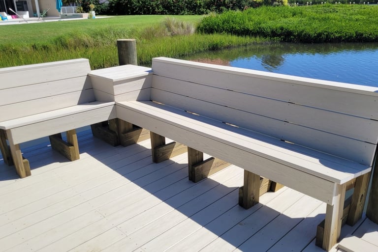 Custom L-shaped composite deck bench built on a backyard dock overlooking a scenic waterway.