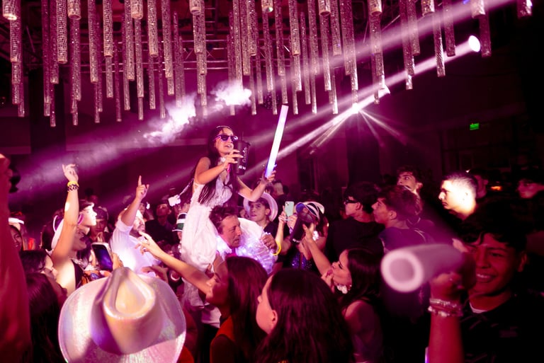 Quinceañera celebrando con sus invitados en pista de baile con luces violetas