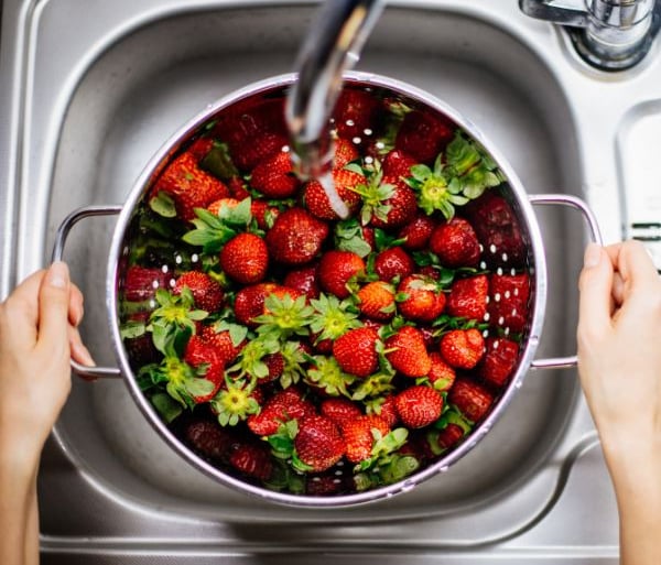 Someone washing strawberries in the sink