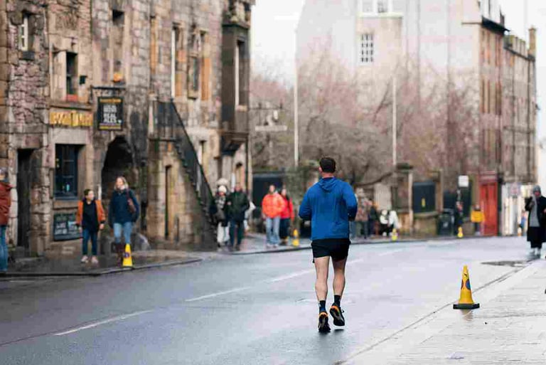 Man jogging on wet urban street with historic stone buildings in background