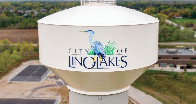 Aerial view of the City of Lino Lakes water tower featuring a blue heron logo and local landscape.