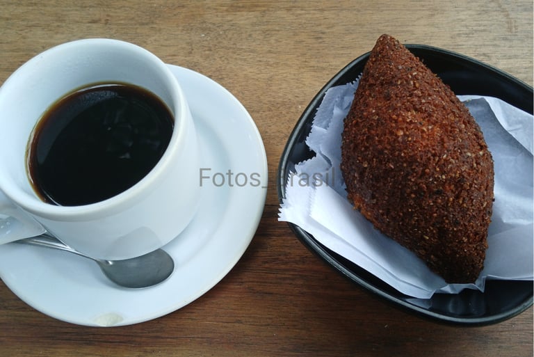 [Download] Uma xícara de café fumegante sobre um pires branco e num pratinho, um kibe dourado...