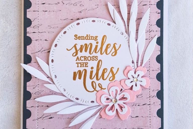Greeting card with the message "Sending smiles across the miles" in gold on a round white cutout. Pi