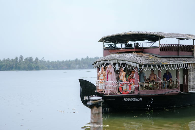 An Indian bride in a pink lehenga arrives by traditional houseboat on the Kerala backwaters.