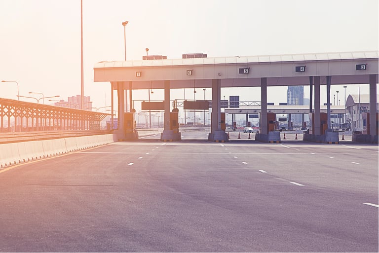 Empty highway toll plaza with sunlight representing an automated toll collection system.