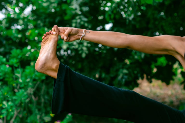 Close-up of yoga pose holding big toe with Om tattoo and blessing band, mindful essentials