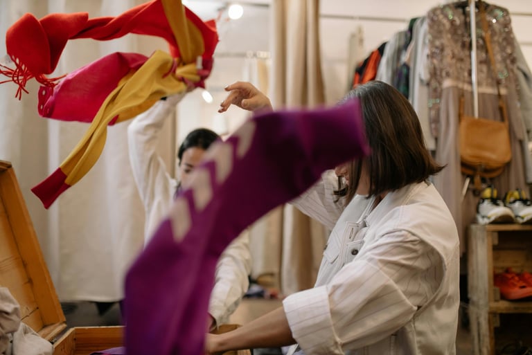 Two people standing with their arms up mid-throw tossing donated clothes into the air