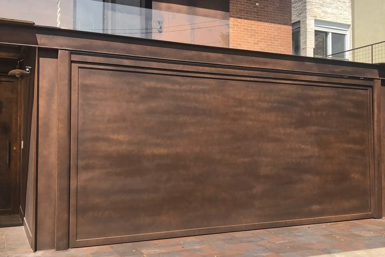 Portão de garagem basculante de alumínio com acabamento em pintura especial na cor bronze, em frente a uma casa de tijolinhos