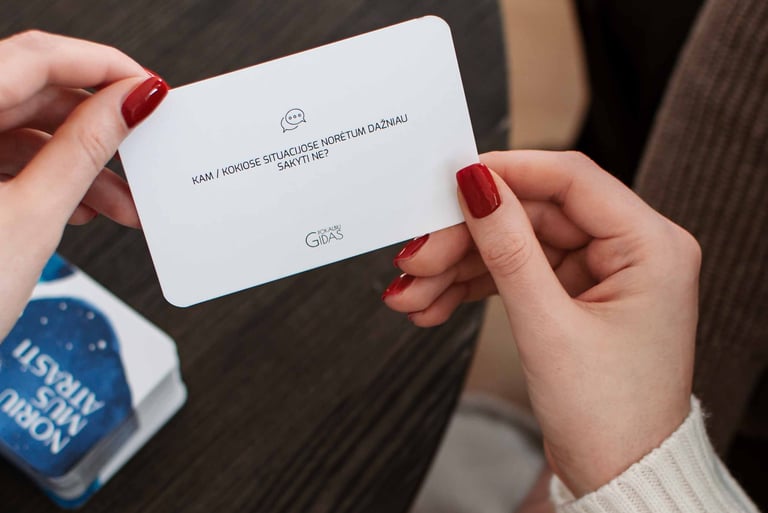 Moteris laiko rankose pokalbių kortelę poroms.