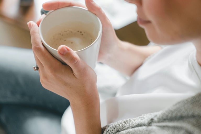 Artimas kadras moters, laikančios rankose kavos puodelį. Simbolizuojant laiko skyrimą sau.