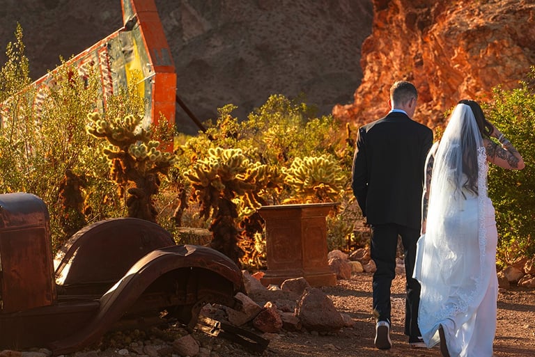 a bride and groom walking down a dirt road