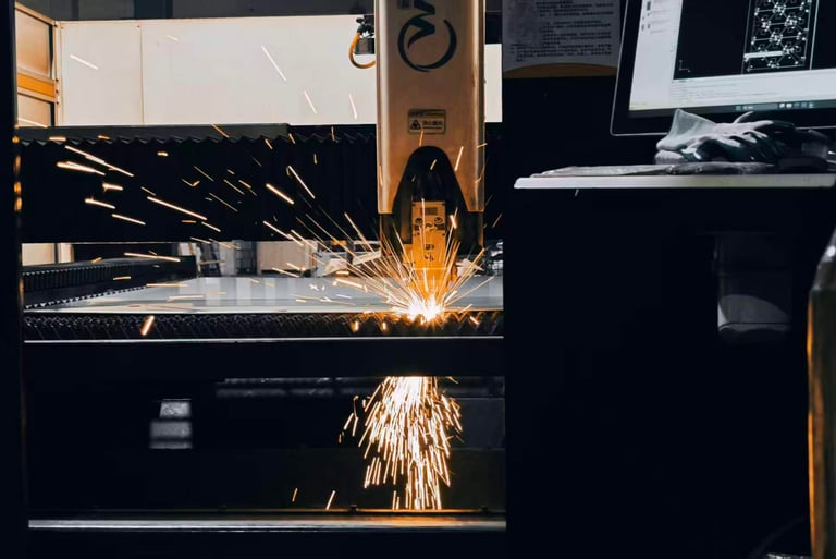 Industrial CNC fiber laser cutting machine processing a metal sheet with bright sparks in a factory.