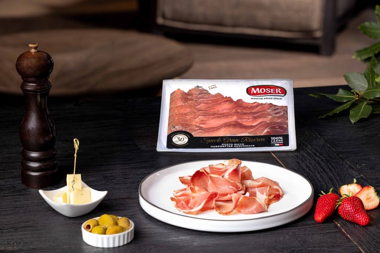 Speck Gran Riserva Moser servito in degustazione con formaggio, olive e fragole