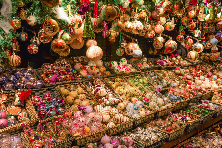 Hand-painted glass Christmas ornaments displayed in wicker baskets at a festive European holiday market.
