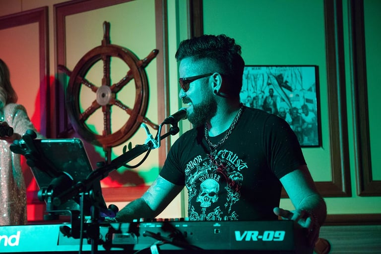 Singer Leo Couto playing a Roland keyboard, looking to the side, wearing sunglasses.