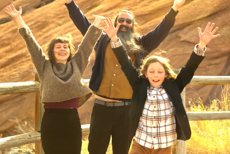 A family, mother father and son, throw their hands in the air at Red Rocks in Colorado