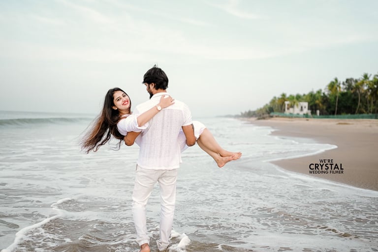 Save the date photograph groom walking on the beach lifting the bride in hand with white costumes