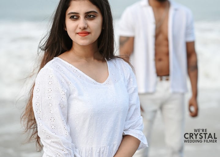 Save the date photoshoot in which bride and groom posing in white costumes on a beach in Kerala