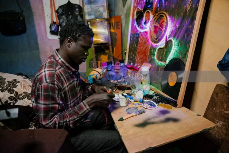 A local artist in a workshop creates handmade jewelry and neon wall art in Kibera.