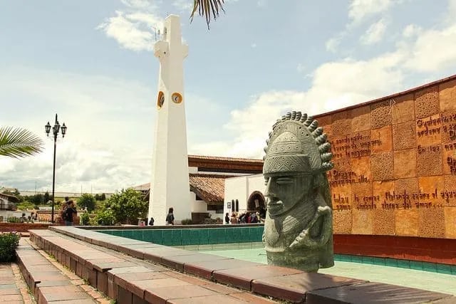 The white clock tower and indigenous monument in Guatavita town square during a private day tour.