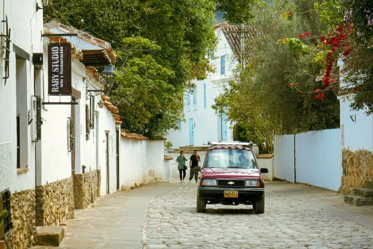 Street-level view of whitewashed colonial houses and a vintage jeep in the town of Villa de Leyva