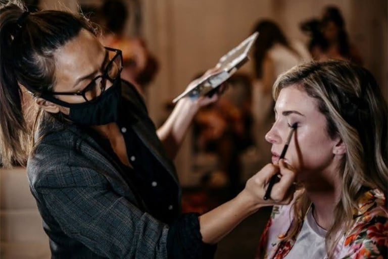 Professional makeup artist Cha Sloan applying eye shadow to a bride for a wedding ceremony.