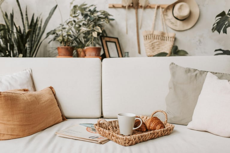 Cream linen sofa with woven pillow, styled with potted plants, coffee mug and woven tray