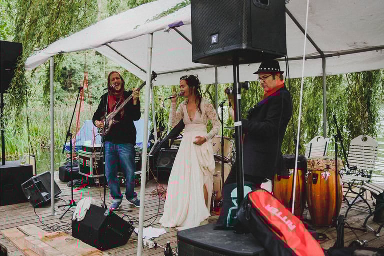 Braut singt mit einer Band auf einer Bühne.