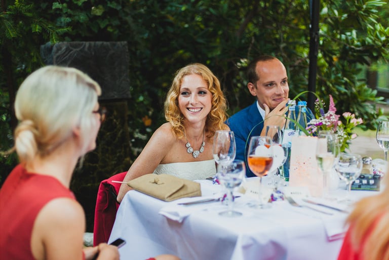 Lächelndes Brautpaar, das an einem Tisch sitzt.