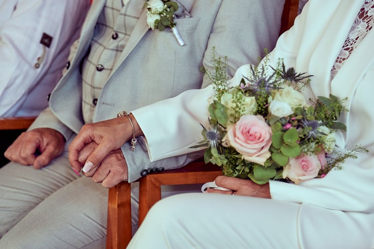 Braut und Bräutigam halten sich während einer Hochzeitszeremonie an den Händen.