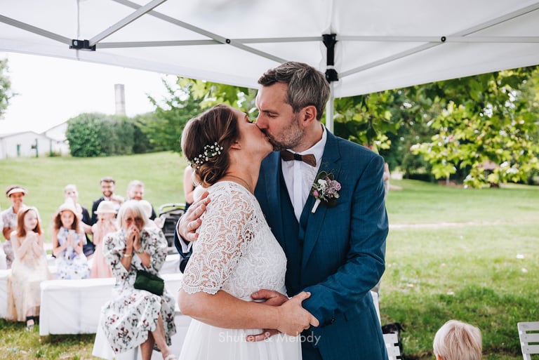 Bride and groom sharing a first kiss.