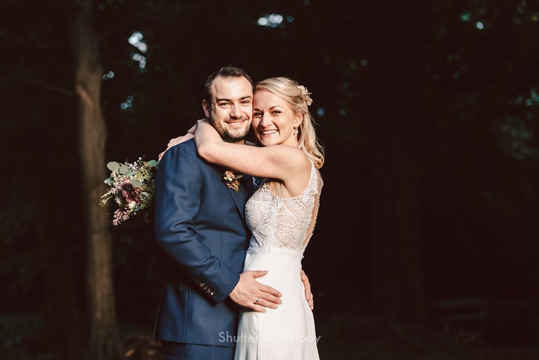 Portrait of bride and groom hugging and laughing.