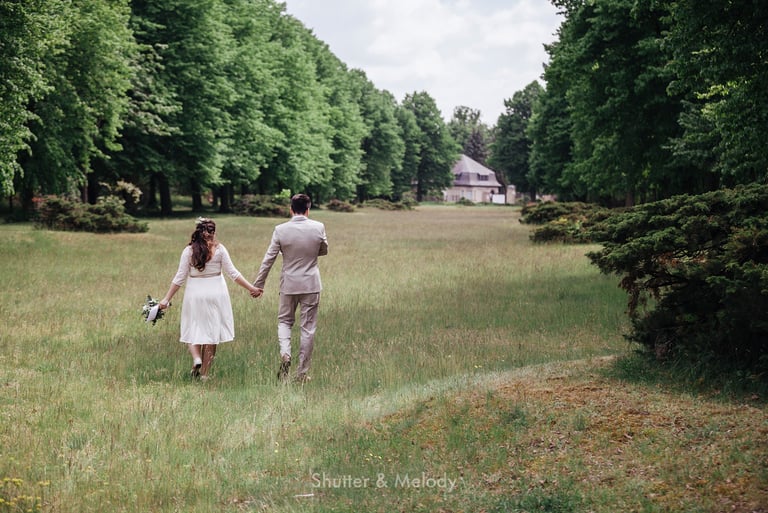 Bride and groom walking in a meadow.