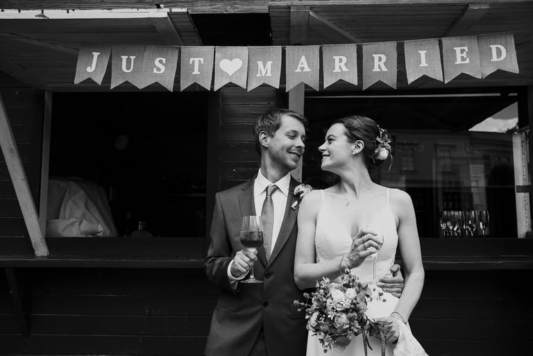 Bride and groom drinking wine under a Just Married sign.