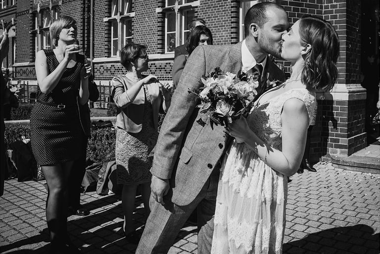 Groom kissing bride after exiting civil registry.