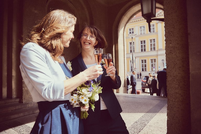 Ein lesbisches Paar stößt mit einem Glas Sekt an.