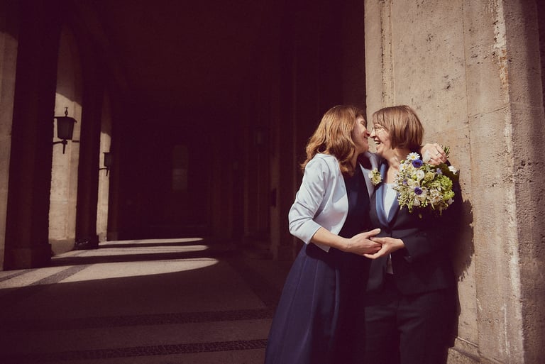 A happy newlywed lesbian couple leaning against a wall.