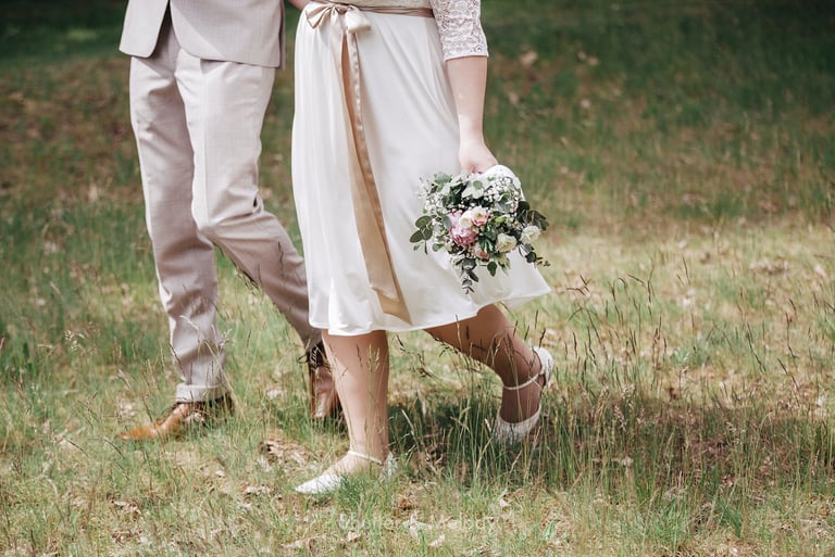 Bride and groom walking on a meadow.