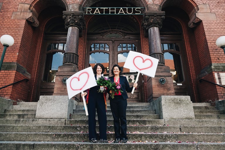 Zwei Bräute stehen vor dem Rathaus von Pankow.