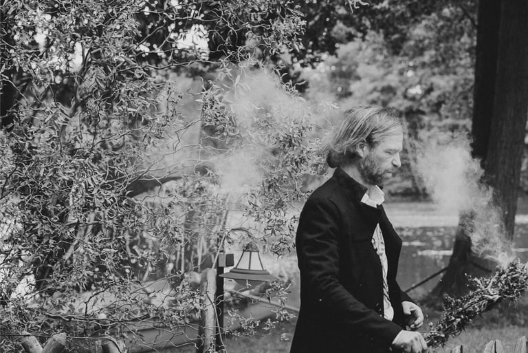 A man clearing up area by burning herbs.