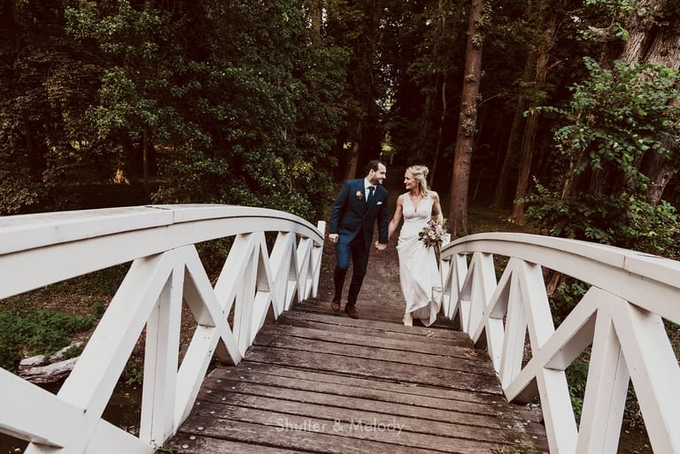 Bride and groom walking over a bridge looking at each other.