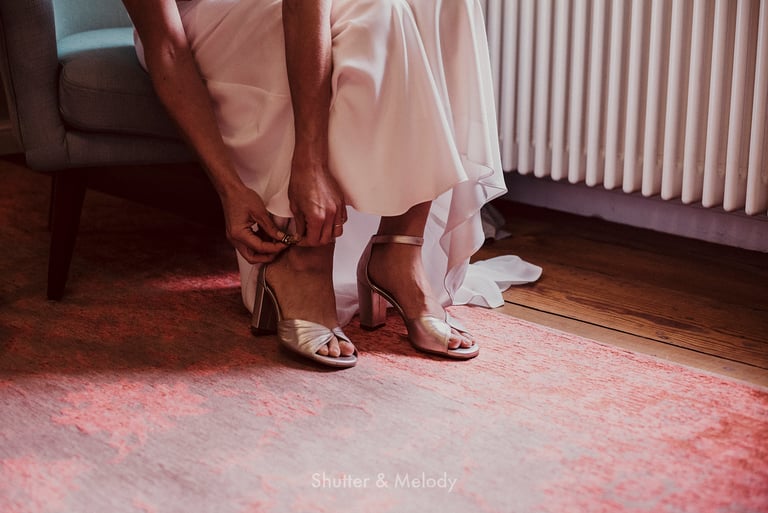 Bride tying her shoe strap.