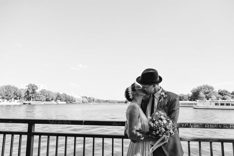 Bride and groom kissing by the river on a sunny day.