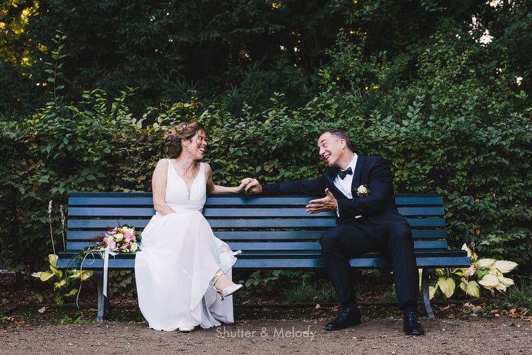 Bride and groom sitting on a blue bench.